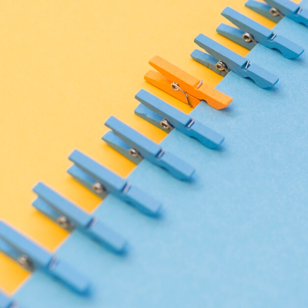 Orange clothespin surrounded by blue ones