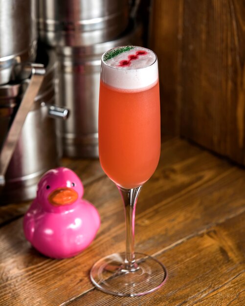 Orange cocktail in champagne glass garnished with green and red sparkles