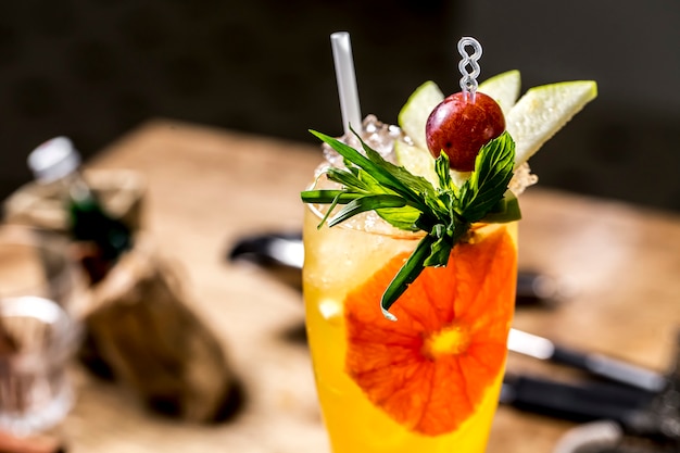 Foto gratuita cocktail arancio con la vista laterale della mela della menta dell'uva di dragoncello