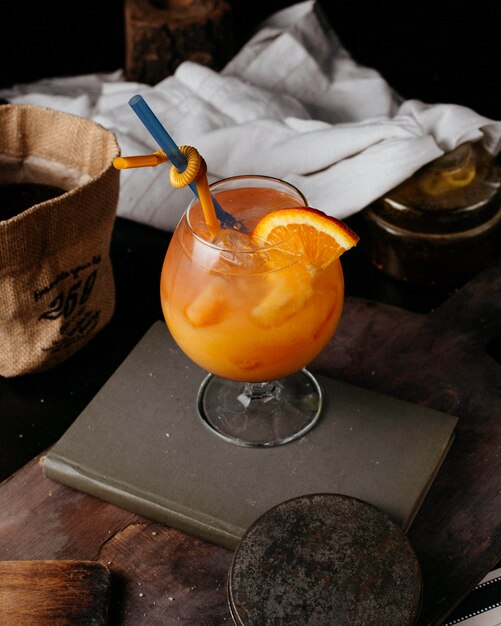 orange coctail with fresh orange juice ice and straws on book