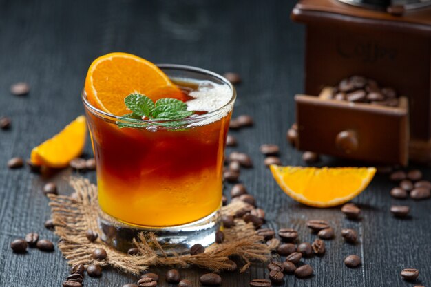 Апельсиновый и кофейный коктейль на темной поверхности.