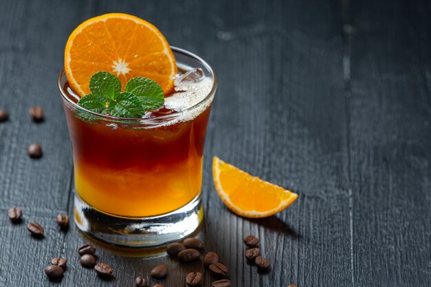 Orange and coffee cocktail on the dark surface.