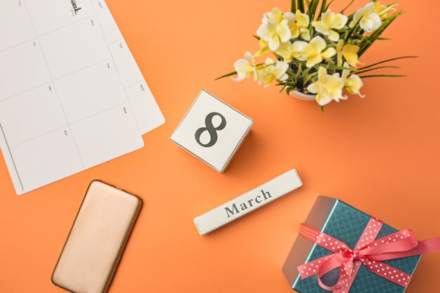 Orange desk with phone, gift, flowers and notebook