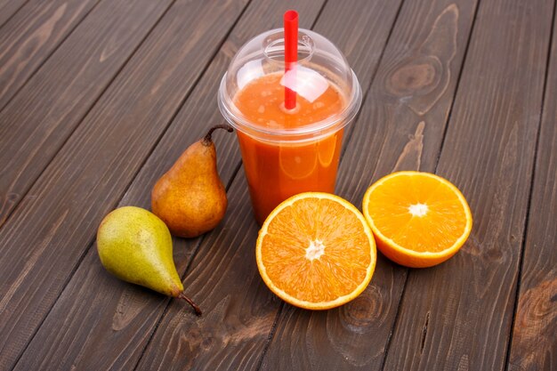 orange detox coctail with oranges and pears lies on wooden table