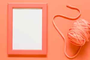 Бесплатное фото Оранжевая пустая рамка и клубок веревки