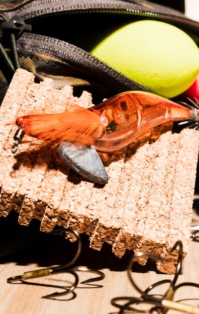 An orange fishing lure with fishing float and corkboard