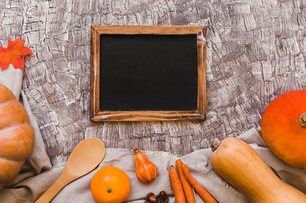 Orange fruit and vegetables near blackboard