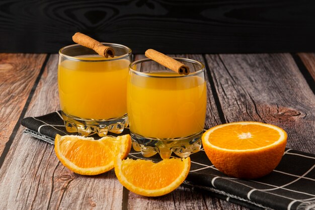 Orange fruit with a glass of juice and cinnamon sticks