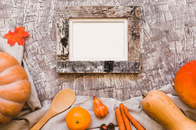 Orange fruits and vegetables near spoon and frame