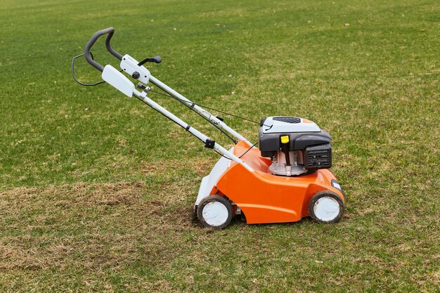 緑の草の上に地面に立っているオレンジ色の草刈り機