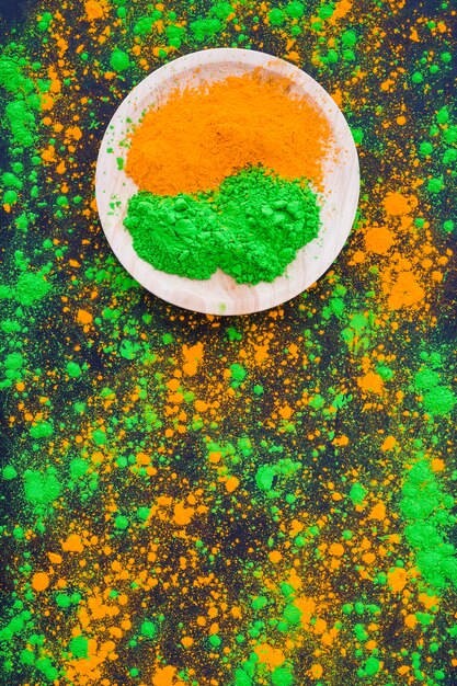 An orange and green powder on wooden plate with splatter backdrop