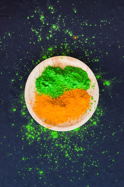 Оранжевый и зеленый порошок на деревянной тарелке