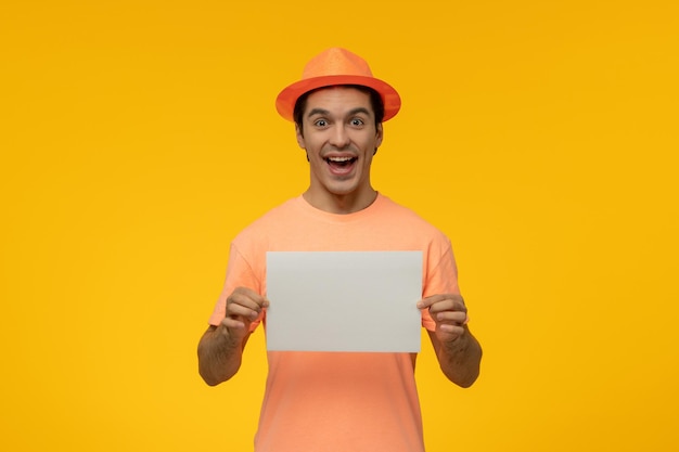 Orange hat cute young guy in orange tshirt with the hat smiling and holding a paper