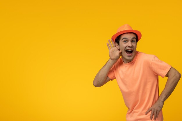 Orange hat handsome pretty guy in orange tshirt with the hat eavesdropping excitingly