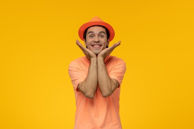 Оранжевая шляпа, красивый симпатичный парень в оранжевой футболке со шляпой, очень счастливый и улыбающийся