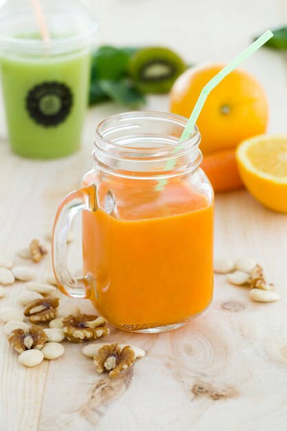 Orange juice in glass, nuts and fresh fruits on wooden backgroun