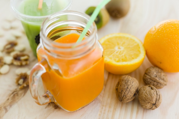 Orange juice in glass, nuts and fresh fruits on wooden backgroun