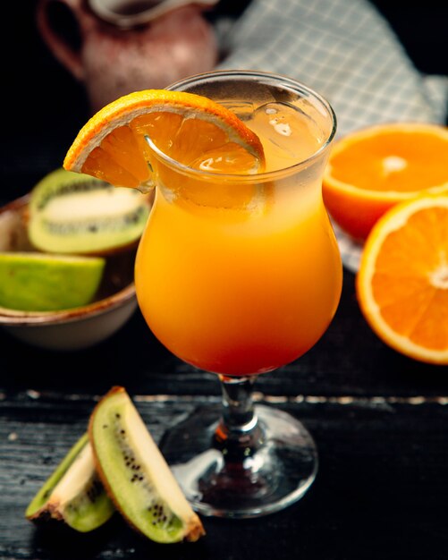 Orange juice with ice cubes and kiwi slices.