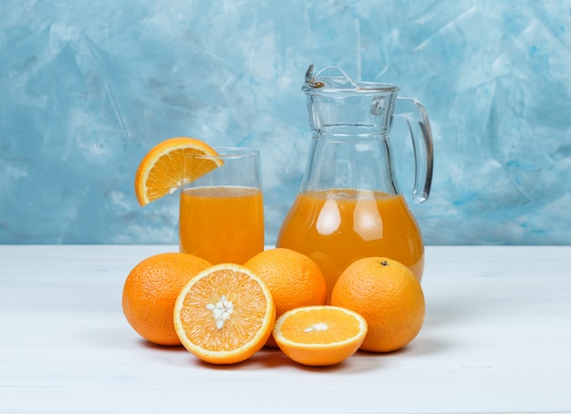 Free photo orange juice with oranges in jug and glass