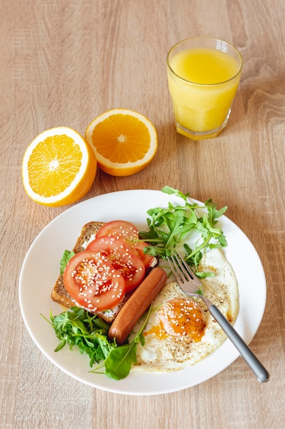 Orange juice with a plate of fried eggs and vegetable sandwich