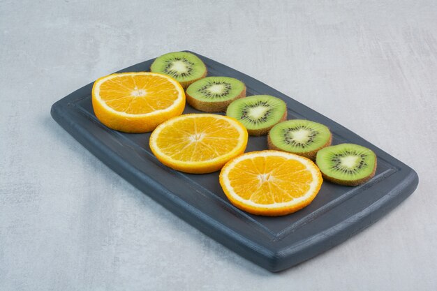 Orange and kiwi slices on dark plate