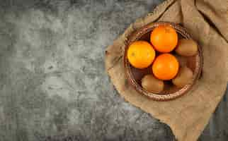 Free photo orange and kiwies in a bowl on a burlap.