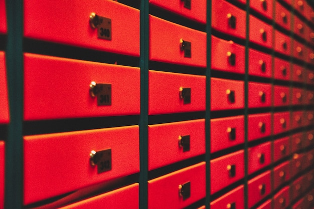 Оранжевые почтовые ящики в многоквартирном жилом доме. четные ряды пронумерованных почтовых ящиков. концепция переписки в городе. вы можете использовать его в качестве фона для своего объявления. копировать пространство
