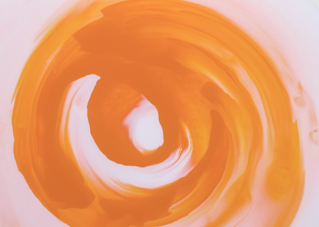 Оранжевые мазки, образующие круглую форму на белом холсте