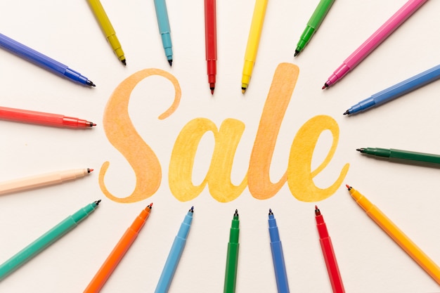 Orange painted lettering SALE on white background between markers