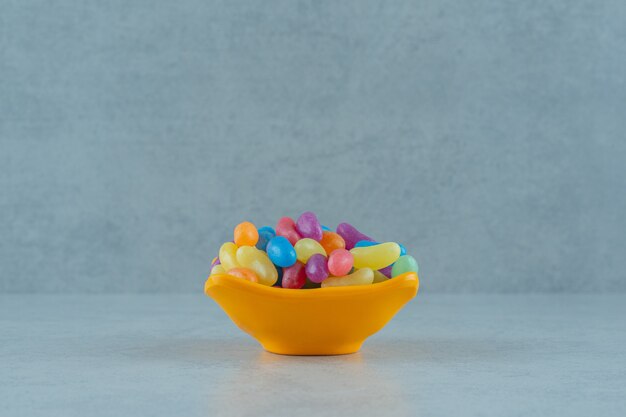 An orange plate of colorful jelly bean candies on white surface