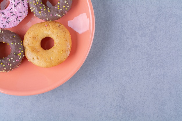 Un piatto arancione di deliziose ciambelle al cioccolato con spruzza.