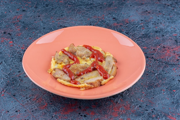 달걀 프라이와 고기가 들어간 주황색 접시.