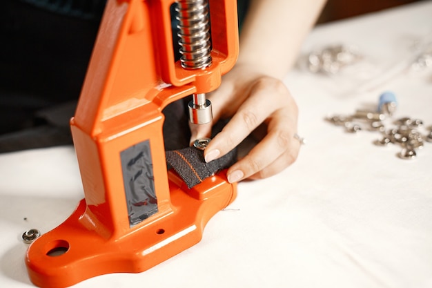 Free photo orange press for clothes. buttons on fabric. woman with sewing tools