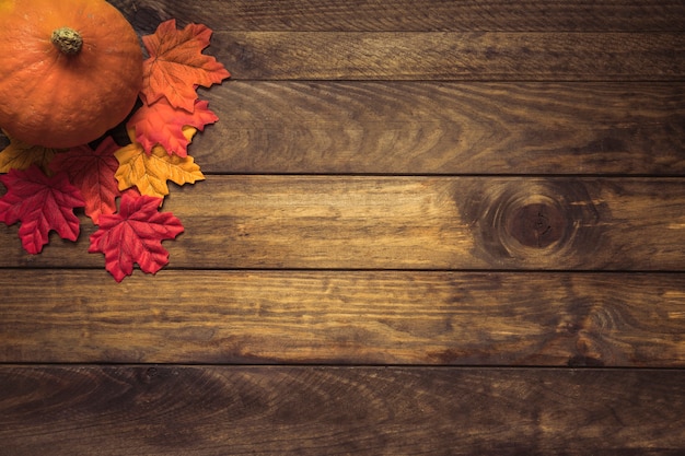 Orange pumpkin lying with autumn leaves