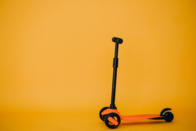 Orange scooter isolated in studio on yellow background