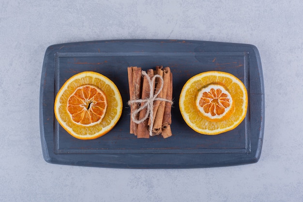 Orange slice on dark board with aromatic cinnamon sticks. 