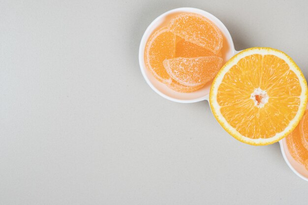 Orange slice and jelly candies on white plate