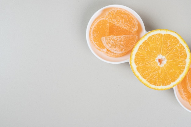 Orange slice and jelly candies on white plate