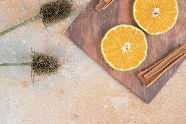 Orange slices and cinnamon sticks on wooden board.