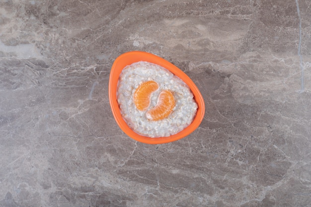 Orange slices on top of porridge in a bowl, on the marble background. igh quality photo