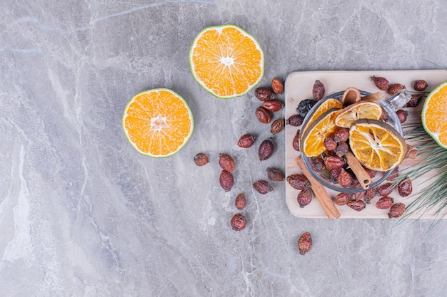 Free photo orange slices with dry hips and cinnamons on a grey platter