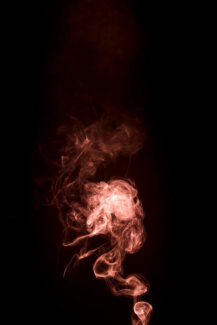 Free Photo an orange smoke rising up on black background