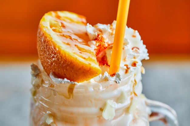 Orange smoothie with sprinkles and straw on the bright surface 