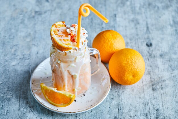 Orange smoothie with sprinkles and straw on the white plate 