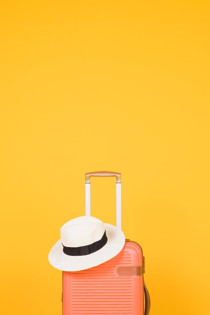 Оранжевый чемодан и белая шляпа