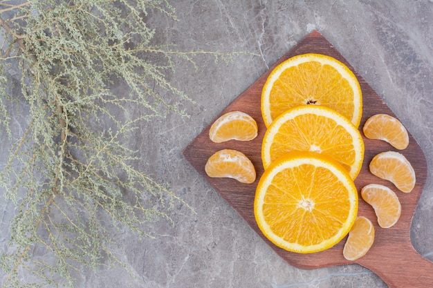 Ломтики апельсина и мандарина на деревянной доске.
