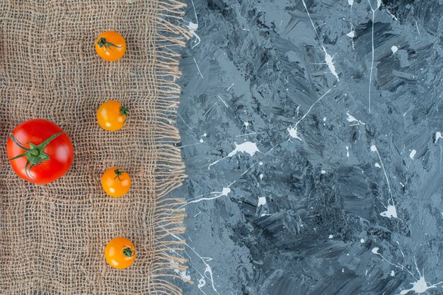 無料写真 大理石の背景に、黄麻布のナプキンにオレンジ色のトマトと赤いトマト。