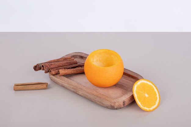 Orange with cinnamon on wooden board .