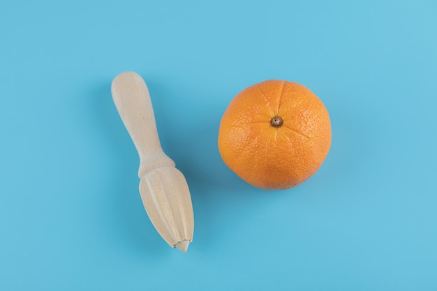 Orange and wooden reamer on blue table.