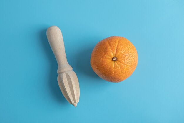 Orange and wooden reamer on blue table. 